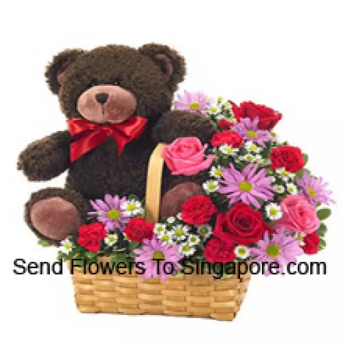Una hermosa canasta hecha de rosas rojas y rosadas, claveles rojos y otras flores moradas surtidas junto con un lindo oso de peluche de 14 pulgadas de altura
